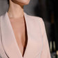 A beige suit with a peplum jacket and tapered trousers